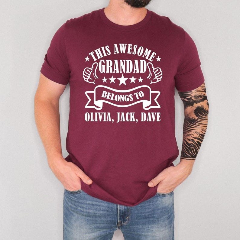 “This Awesome Grandad Belongs To” personalised t shirt featuring custom family names with bold typography and decorative star graphics. Sentimental grandad gift shirt designed for Fathers Day, Christmas gifting, birthday celebrations and family gatherings. Comfortable unisex family tee for grandfathers who enjoy personalised clothing with meaningful grandchildren inspired artwork and casual everyday fashion.