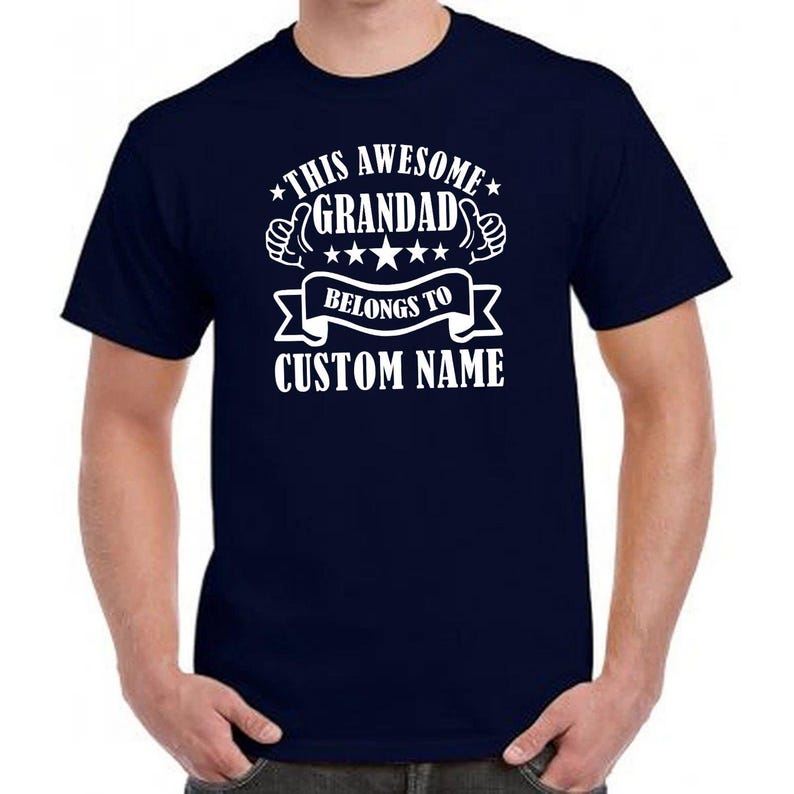 Funny personalised grandad shirt featuring custom names and bold typography graphic artwork with stars and thumbs up illustrations. Family inspired unisex t shirt suitable for Fathers Day presents, Christmas gifts for grandad, birthday surprises and everyday casual outfits. Personalised family clothing designed for proud grandfathers who enjoy meaningful keepsake apparel and custom graphic fashion.