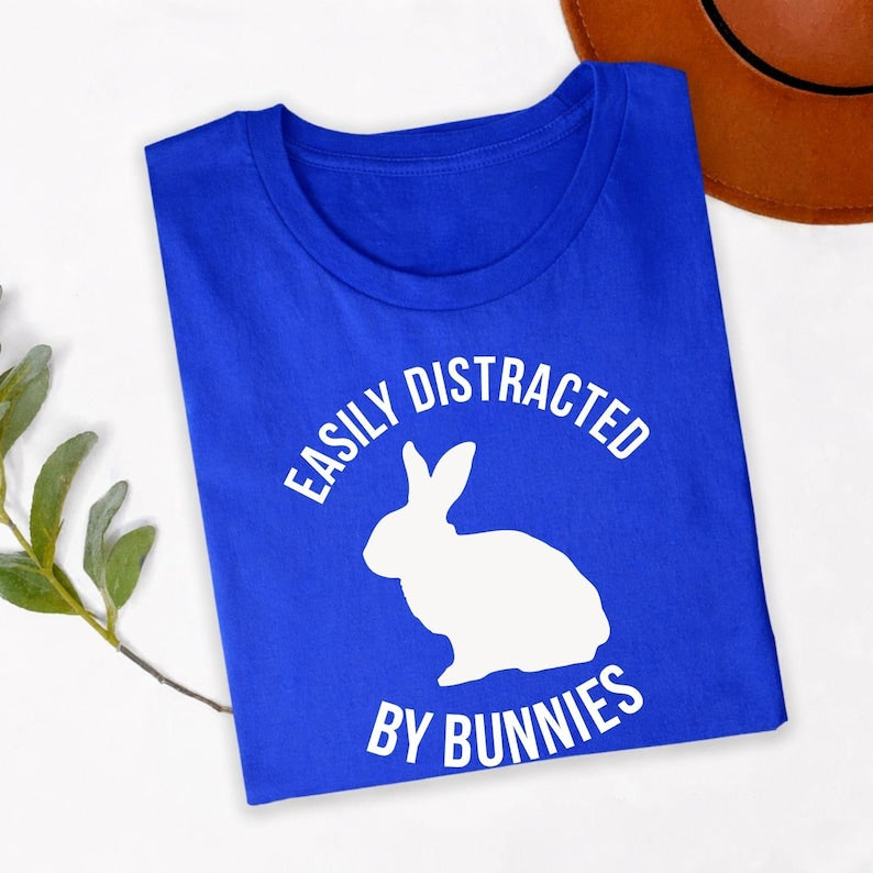 Easily Distracted By Bunnies T Shirt is perfect for bunny shows, pet adoption events, rabbit rescue fundraisers, Easter celebrations, farm visits, countryside holidays, family gatherings, birthdays, casual everyday wear, weekend outings, pet meetups, animal charity events, outdoor adventures, school fairs, and community festivals. Designed by Teezora Prints with a bold rabbit silhouette and modern typography to celebrate every bunny lover's lifestyle.