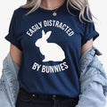 Easily Distracted By Bunnies T Shirt created for bunny lovers, rabbit owners, pet parents, animal enthusiasts, rabbit breeders, rescue volunteers, farm lovers, veterinary staff, and anyone who instantly smiles whenever they see a bunny. Featuring a bold rabbit silhouette with clean typography, this premium graphic tee from Teezora Prints celebrates a love for adorable rabbits while delivering exceptional comfort, premium print quality, stylish everyday fashion, and a fun personality for every bunny enthusia