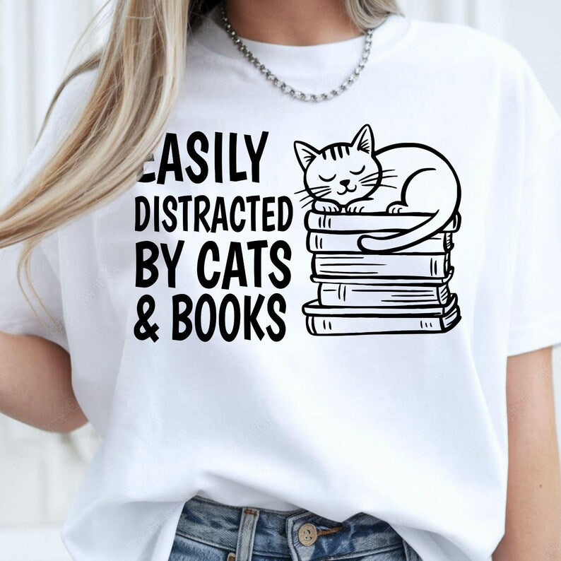 Funny Cat Shirt, Easily Distracted By Cats And Books Shirt, Book Lover T Shirt, Cat Lover Tee, Bookworm Shirt, Reading Shirt, Librarian Shirt, Teacher Tee, Sleeping Cat Shirt, Book Stack Shirt, Reader Gift, Cat Mum Shirt, Cat Dad Shirt, Animal Lover Tee, Literary Shirt, Premium Graphic T Shirt by Teezora Prints, Reading Apparel, Novel Lover Shirt, Library Shirt, Casual Book Lover Clothing, Bookish Tee, Reading Graphic Shirt, Cat Gift, Book Gift.