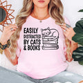 Easily Distracted By Cats & Books T Shirt makes a thoughtful gift for readers, librarians, teachers, students, authors, writers, book club members, cat mums, cat dads, pet owners, daughters, sons, wives, husbands, sisters, brothers, and friends. Designed by Teezora Prints, this premium graphic shirt is perfect for birthdays, Christmas, Teacher Appreciation, Mother's Day, Father's Day, graduation gifts, book club events, and memorable gifts for every book and cat enthusiast.