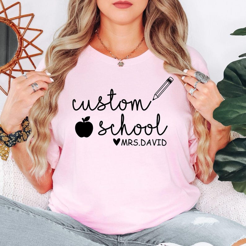 Personalised Teacher T Shirt featuring custom school name and teacher name with an apple and pencil design created for teachers, tutors, nursery staff, and classroom assistants. Teezora Prints offers premium teacher apparel for customers searching personalised teacher gifts, custom school shirts, teacher appreciation clothing, classroom uniforms, education apparel, teacher fashion, back to school outfits, and personalised teaching shirts.