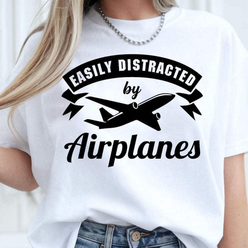 Easily Distracted By Airplanes t shirt created for aviation enthusiasts, pilots, cabin crew, aircraft mechanics, aerospace engineers, plane spotters, aviation students, frequent travellers, airport workers, flight instructors, and anyone who instantly looks up whenever an aircraft flies overhead. Featuring a bold airplane silhouette with modern typography, this premium graphic tee celebrates a lifelong passion for aviation while delivering exceptional comfort, premium print quality, and stylish everyday fas