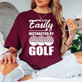 Teezora Prints Funny golf t shirt featuring the quote Sorry I'm Easily Distracted By Golf with bold typography and golf ball graphics designed for golfers and sports enthusiasts. Ideal for customers searching golf lover shirts, funny golfer tees, golf player clothing, golf tournament apparel, golf gifts for men and women, golf club fashion, weekend golfer outfits, premium golf graphic t shirts, golf lifestyle apparel, and unique golf clothing with modern typography.