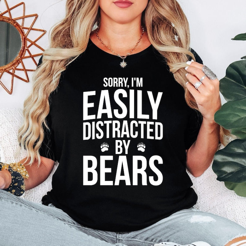 Teezora Prints Sorry I'm Easily Distracted By Bears T Shirt created for bear lovers, wildlife enthusiasts, hikers, campers, nature lovers, outdoor adventurers, national park visitors, forest explorers, animal lovers, and anyone fascinated by bears. Featuring bold typography with paw print accents, this premium graphic tee celebrates a love for wildlife while providing exceptional comfort, professional print quality, stylish everyday fashion, and a fun personality for every outdoor enthusiast.
