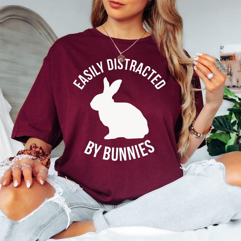 Looking for the perfect gift for someone obsessed with rabbits? This Easily Distracted By Bunnies T Shirt from Teezora Prints features a bold rabbit silhouette with stylish typography that every bunny owner will instantly relate to. Professionally printed on a premium quality unisex t shirt, it offers exceptional comfort, long-lasting durability, and timeless style. Perfect for birthdays, Christmas, Easter, Mother's Day, Father's Day, pet adoption celebrations, and thoughtful gifts for bunny lovers.