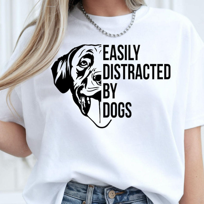 Perfect for dog lovers, pet parents, dog mums, dog dads and animal enthusiasts, this Easily Distracted by Dogs shirt features a playful dog illustration with a bold graphic slogan that captures every dog lover's personality. Whether you're out walking your pup or relaxing with your furry friend, this premium t-shirt delivers comfort and style. Professionally printed in the UK by TeezoraPrints using high-quality materials.