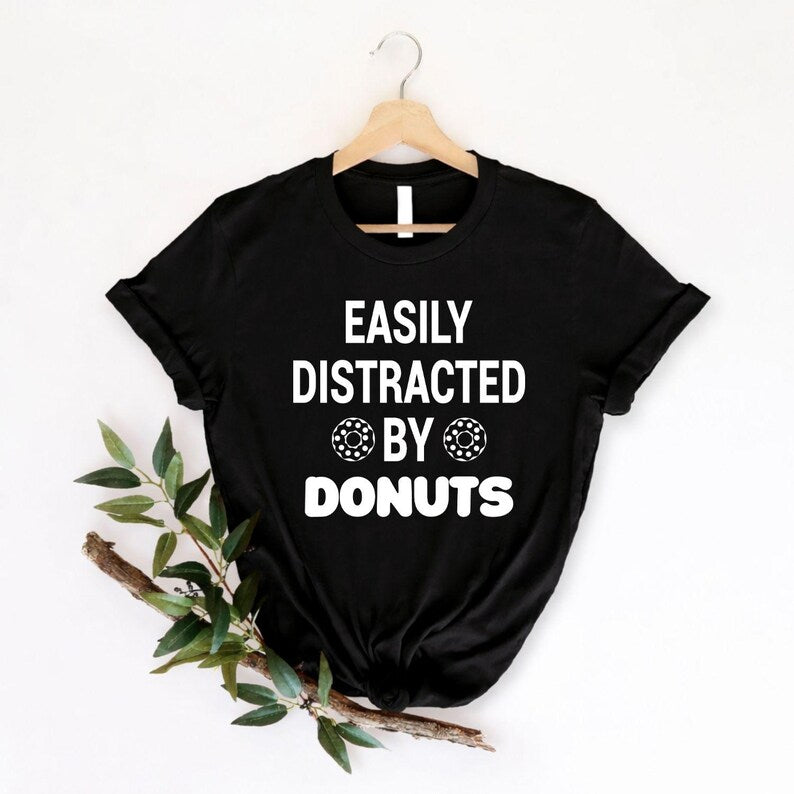 Searching for the perfect gift for a donut lover? This Easily Distracted by Donuts shirt is a fun choice for birthdays, Christmas, Mother's Day, Father's Day or any special occasion. Featuring playful donut graphics and a humorous slogan, every premium shirt is professionally printed in the UK by TeezoraPrints for a memorable gift they'll love.