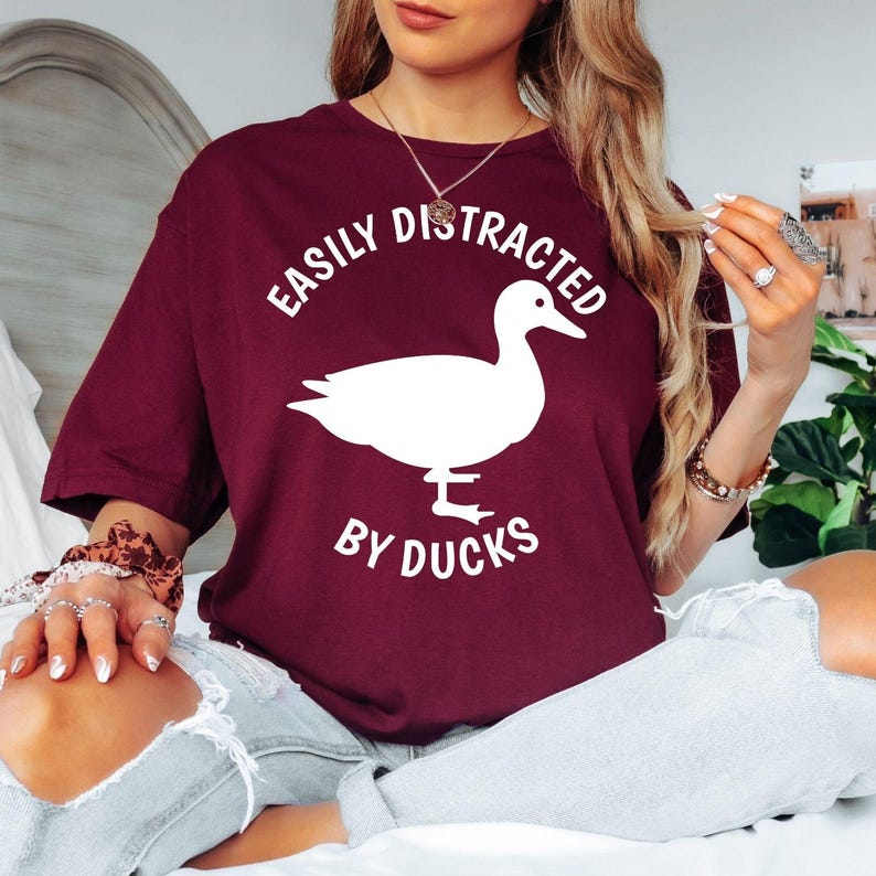Show everyone your love for ducks with this Easily Distracted by Ducks graphic t-shirt featuring a bold duck silhouette and stylish typography. The soft premium cotton and comfortable unisex fit make it perfect for everyday wear, outdoor adventures and casual weekends. Every order is made to order and professionally printed in the UK by TeezoraPrints.