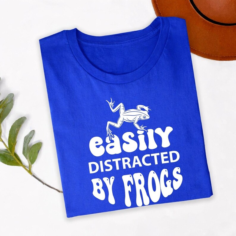 Searching for the perfect gift for a frog lover? This Easily Distracted by Frogs shirt is a thoughtful choice for birthdays, Christmas, Mother's Day, Father's Day or any special occasion. Featuring a detailed frog graphic and humorous slogan, every premium shirt is professionally printed in the UK by TeezoraPrints for a memorable and unique gift.
