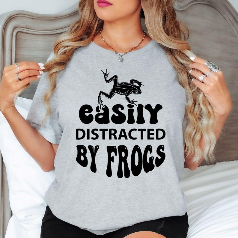 Celebrate your passion for frogs and the natural world with this Easily Distracted by Frogs shirt featuring bold typography and an eye-catching amphibian illustration. Whether you're relaxing outdoors, exploring forests or spending time near lakes and ponds, this premium t-shirt delivers all-day comfort. Every shirt is proudly printed in the UK by TeezoraPrints.