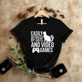 Looking for the perfect gift for someone who loves both cats and gaming? This Easily Distracted By Cats And Video Games T Shirt from Teezora Prints combines a bold typography layout, cat silhouette, and gaming controller graphic into one eye-catching design. Professionally printed on a premium quality unisex t shirt, it's perfect for birthdays, Christmas, gaming tournaments, cat lovers, streamers, esports fans, casual gamers, and anyone proud of their gaming lifestyle.