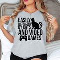 Easily Distracted By Cats And Video Games T Shirt makes an unforgettable gift for gamers, cat mums, cat dads, streamers, Twitch creators, YouTubers, esports players, brothers, sisters, sons, daughters, husbands, wives, friends, coworkers, and pet lovers. Designed by Teezora Prints, this premium graphic shirt is perfect for birthdays, Christmas, Father's Day, Mother's Day, gaming events, Secret Santa, and thoughtful gifts for anyone obsessed with cats and video games.