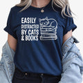 Looking for the perfect gift for someone who loves books and cats? This Easily Distracted By Cats & Books T Shirt from Teezora Prints features an adorable sleeping cat resting on a stack of books with bold typography that every reader will instantly love. Professionally printed on a premium quality unisex t shirt, it offers exceptional comfort, long-lasting durability, and timeless style. Perfect for birthdays, Christmas, Book Club gifts, Teacher Appreciation, Mother's Day, and thoughtful surprises for read