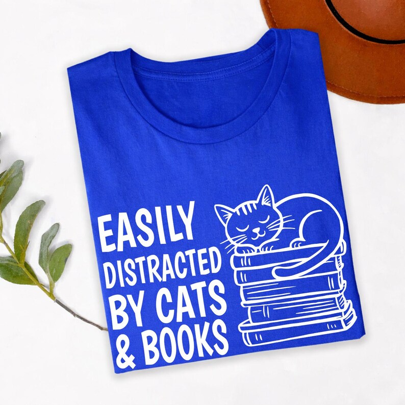 Easily Distracted By Cats & Books T Shirt is perfect for library visits, book club meetings, reading cafés, literary festivals, bookstore shopping, school events, college life, casual weekends, birthdays, holidays, family gatherings, classroom wear, everyday reading sessions, and relaxing evenings at home with your favourite book and cat. Teezora Prints combines premium quality with a charming literary design for true book lovers.