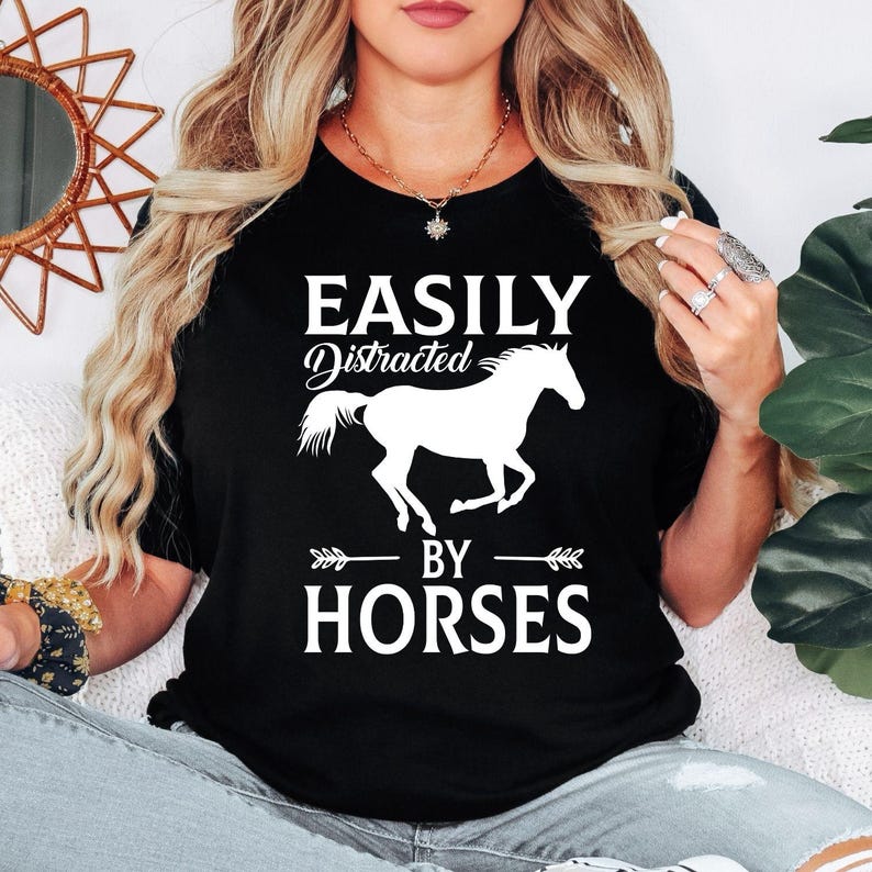 Perfect for horse lovers, equestrians, riders and stable owners, this Easily Distracted by Horses shirt features a striking running horse silhouette with bold typography that captures every equine enthusiast's personality. Whether you're spending time at the stables or enjoying country life, this premium t-shirt offers exceptional comfort. Every shirt is professionally printed in the UK by TeezoraPrints using premium-quality materials.