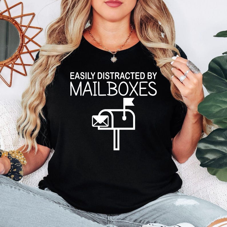 Perfect for postal workers, mail carriers, mailbox collectors and anyone who enjoys quirky everyday humour, this Easily Distracted by Mailboxes shirt features a bold mailbox graphic with a playful slogan. Ideal for workdays, casual wear or showing your love for all things postal. Every premium t-shirt is professionally printed in the UK by TeezoraPrints using high-quality materials.