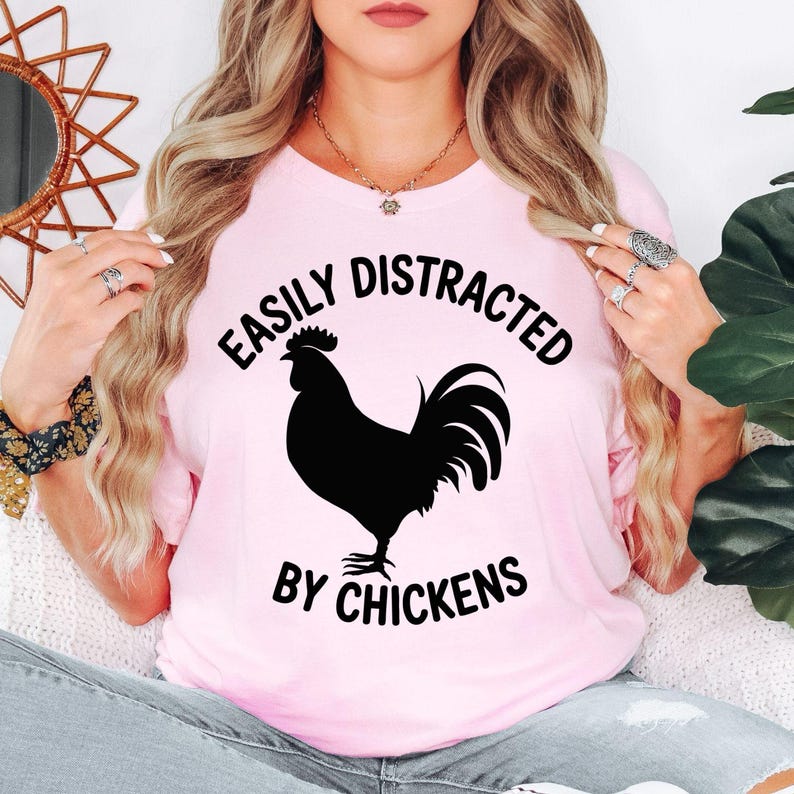 Easily Distracted By Chickens T Shirt featuring a bold rooster silhouette and funny poultry quote designed for chicken keepers, farmers, homesteaders, and animal lovers. Teezora Prints creates premium apparel for customers searching chicken lover shirts, rooster clothing, backyard chicken t shirts, poultry gifts, country lifestyle apparel, farm graphic tees, rural fashion, homestead clothing, premium chicken apparel, and unique farm-themed casual wear.