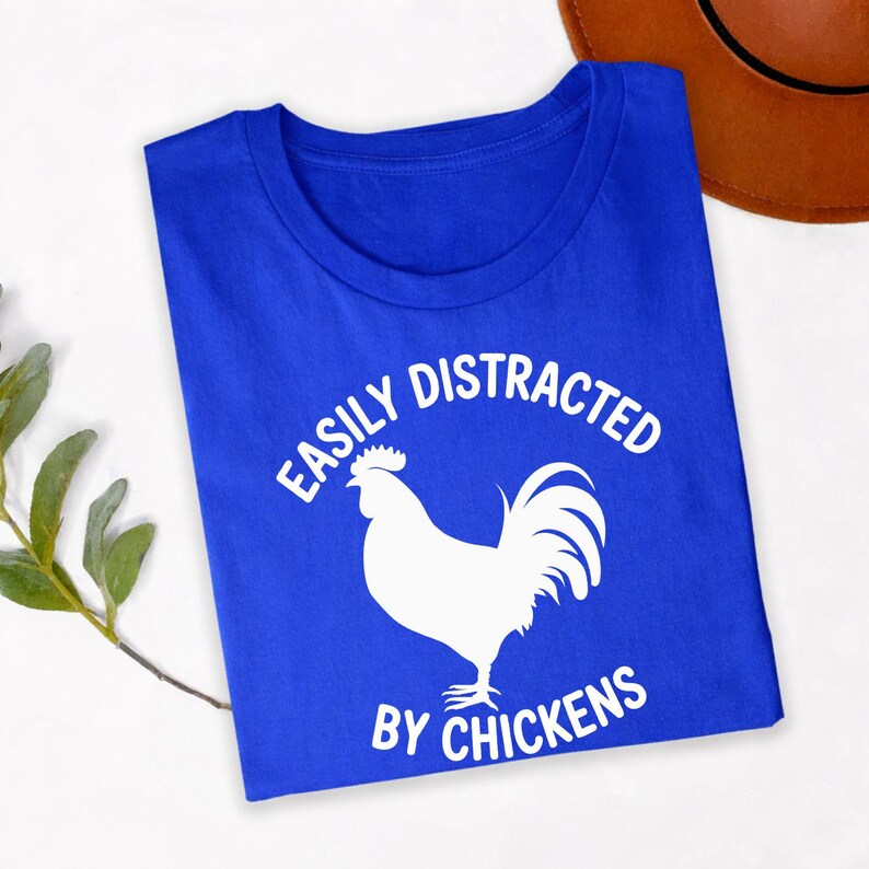 Easily Distracted By Chickens T Shirt makes a thoughtful gift for chicken mums, chicken dads, poultry farmers, backyard chicken owners, homesteaders, rural families, animal lovers, farmers, friends, brothers, sisters, husbands, wives, and anyone passionate about raising chickens. Designed by Teezora Prints, this premium graphic shirt is perfect for birthdays, Christmas, Mother's Day, Father's Day, farm celebrations, retirement gifts, and memorable surprises for poultry enthusiasts.