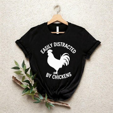 Easily Distracted By Chickens T Shirt created for chicken lovers, backyard chicken keepers, poultry farmers, homesteaders, smallholders, country lifestyle enthusiasts, farm animal lovers, rural families, and anyone who can't resist stopping to admire chickens. Featuring a bold chicken silhouette with modern typography, this premium graphic tee from Teezora Prints celebrates farm life while offering exceptional comfort, premium print quality, stylish everyday fashion, and a fun personality for poultry enthus