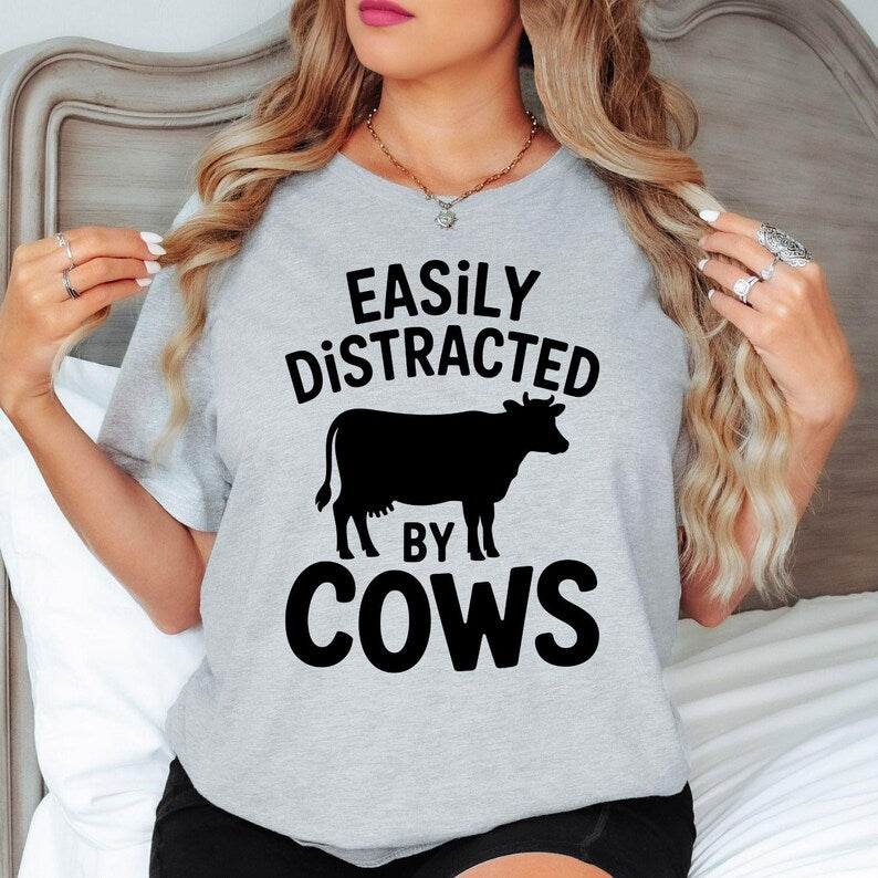 Celebrate your passion for farming and country living with this Easily Distracted by Cows shirt. Whether feeding livestock, exploring the countryside, visiting a dairy farm or spending weekends outdoors, this premium t-shirt keeps you comfortable while showing your love for cattle. Proudly printed in the UK by TeezoraPrints for reliable quality and timeless style.