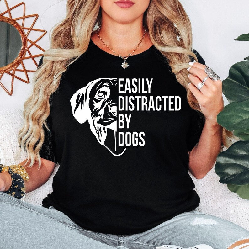 Perfect for dog lovers, pet parents, dog mums, dog dads and animal enthusiasts, this Easily Distracted by Dogs shirt features a playful dog illustration with a bold graphic slogan that captures every dog lover's personality. Whether you're out walking your pup or relaxing with your furry friend, this premium t-shirt delivers comfort and style. Professionally printed in the UK by TeezoraPrints using high-quality materials.