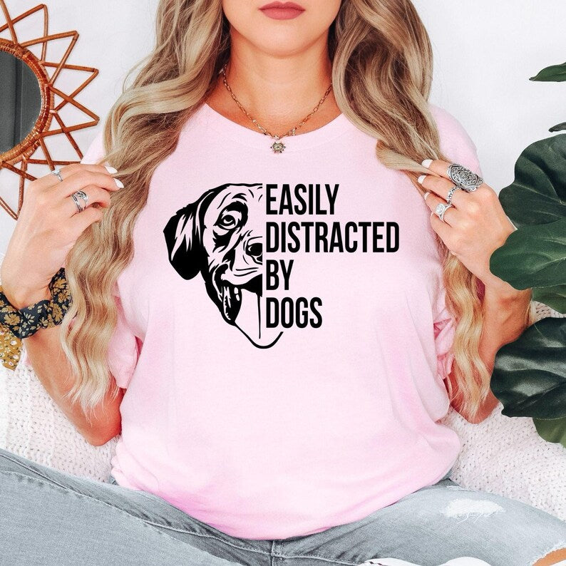 Show everyone you're a proud dog lover with this Easily Distracted by Dogs graphic t-shirt featuring a cute dog illustration and eye-catching typography. The premium unisex fit offers all-day comfort while the fun design makes it perfect for everyday outfits, dog walks and casual weekends. Every shirt is made to order and professionally printed in the UK by TeezoraPrints.