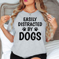 Celebrate your love for dogs with this Easily Distracted by Dogs shirt featuring bold typography and playful paw print graphics. Whether spending time with your pet, travelling, relaxing at home or exploring outdoors, this premium t-shirt offers comfort and style. Every order is proudly printed in the UK by TeezoraPrints for lasting quality.