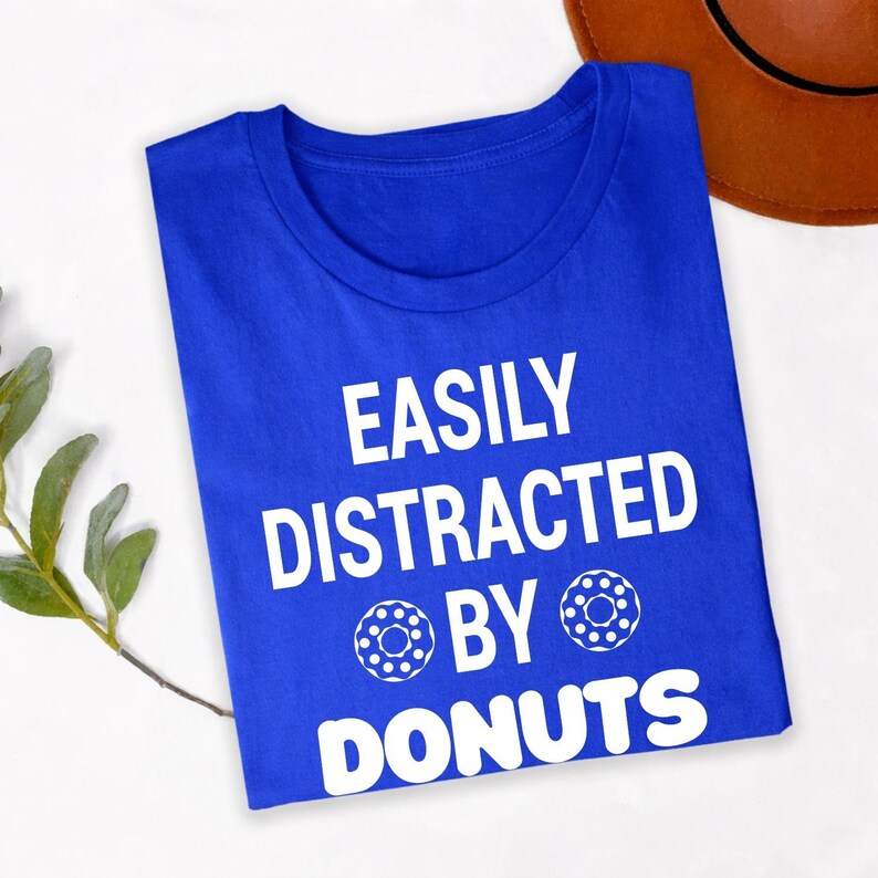 Perfect for coffee shop visits, bakery trips, food festivals, brunch dates, casual weekends, dessert outings, café meetups, holiday celebrations and everyday wear. This Easily Distracted by Donuts shirt combines humour, comfort and style, while every premium t-shirt is professionally printed in the UK by TeezoraPrints using premium-quality materials.
