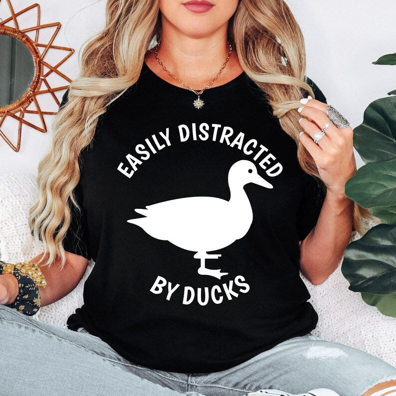 Perfect for duck lovers, bird enthusiasts, wildlife fans and nature lovers, this Easily Distracted by Ducks shirt features a bold duck silhouette with playful typography for a fun everyday look. Whether you're visiting the park, relaxing by the lake or enjoying the countryside, this premium t-shirt delivers lasting comfort. Every shirt is professionally printed in the UK by TeezoraPrints using premium-quality materials.