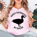 Celebrate your passion for ducks and wildlife with this Easily Distracted by Ducks shirt featuring a bold silhouette design and playful slogan. Whether you're spending time outdoors, exploring local parks or enjoying peaceful lakeside walks, this premium t-shirt offers all-day comfort. Every shirt is proudly printed in the UK by TeezoraPrints for exceptional quality.