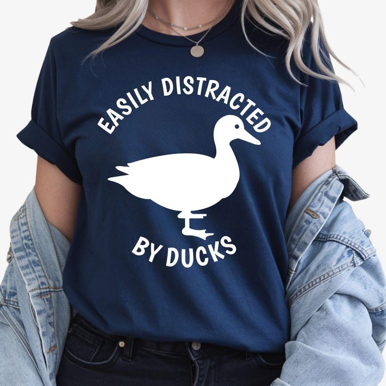 Perfect for duck lovers, bird enthusiasts, wildlife fans and nature lovers, this Easily Distracted by Ducks shirt features a bold duck silhouette with playful typography for a fun everyday look. Whether you're visiting the park, relaxing by the lake or enjoying the countryside, this premium t-shirt delivers lasting comfort. Every shirt is professionally printed in the UK by TeezoraPrints using premium-quality materials.