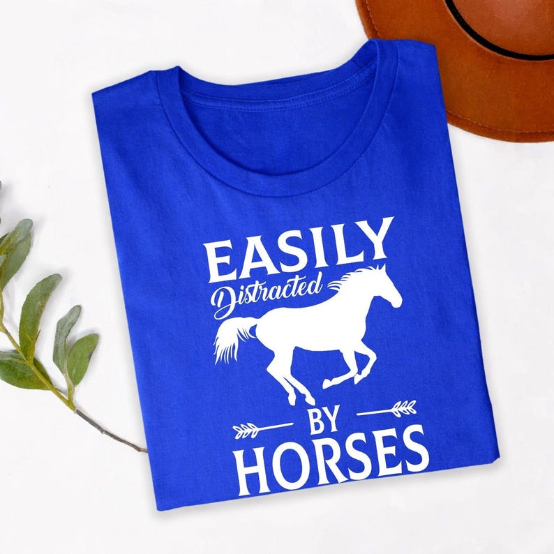 Perfect for horse riding lessons, stable visits, equestrian competitions, country fairs, ranch work, outdoor adventures, farm weekends and casual everyday wear. This Easily Distracted by Horses shirt combines comfort, humour and style, while every premium t-shirt is professionally printed in the UK by TeezoraPrints using high-quality materials.