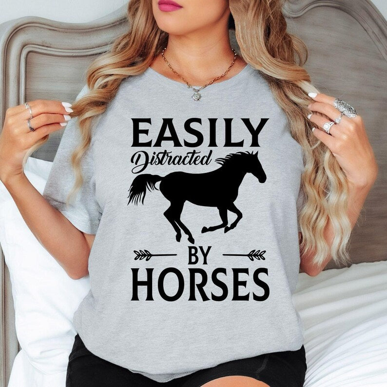Searching for the perfect gift for a horse lover? This Easily Distracted by Horses shirt is an excellent choice for birthdays, Christmas, Mother's Day, Father's Day or any special occasion. Featuring a bold horse silhouette and humorous slogan, every premium shirt is professionally printed in the UK by TeezoraPrints for a memorable gift they'll love.