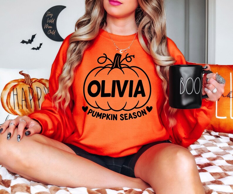 Personalised Pumpkin Season clothing featuring custom name printing and a classic pumpkin illustration, created for autumn lovers who enjoy seasonal activities. Perfect for pumpkin patch visits, Halloween celebrations, autumn walks, family events and cosy weekends. This custom name sweatshirt makes a distinctive personalised gift for women, men, friends, mums, sisters, daughters and pumpkin-loving family